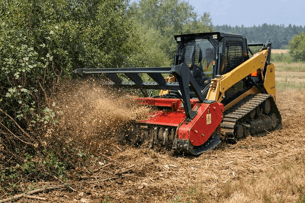 Track skid steer clearing dense brush along rural fence lines